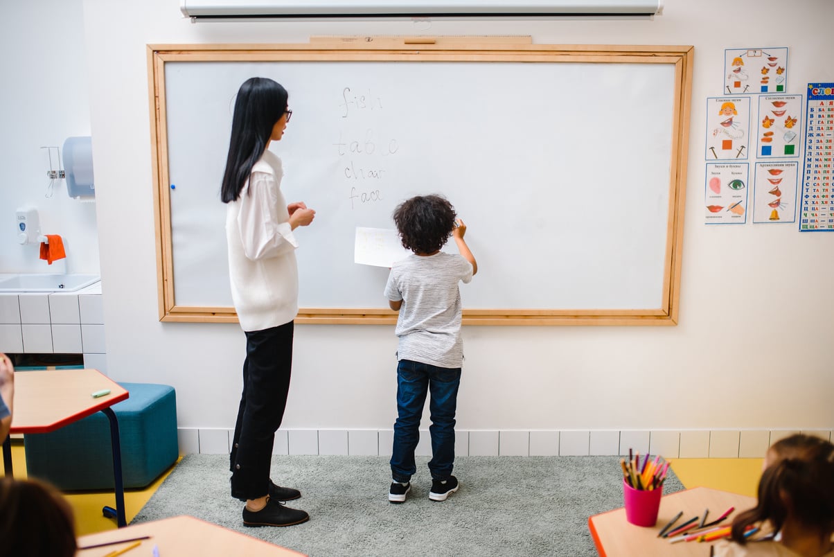 2 Women Standing in Front of Whiteboard